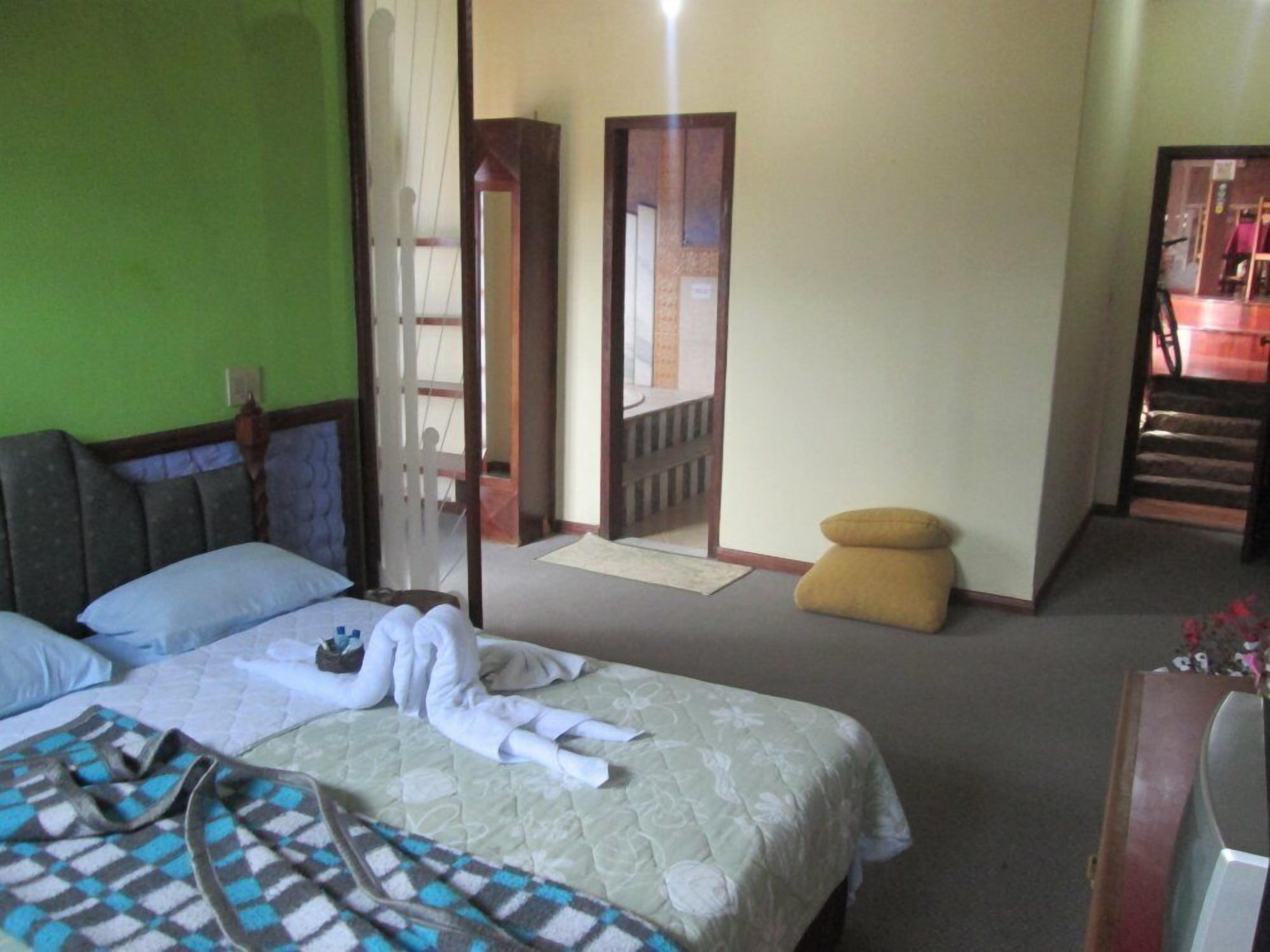 A bedroom with a bed, a chair, a small table, and a mirror.