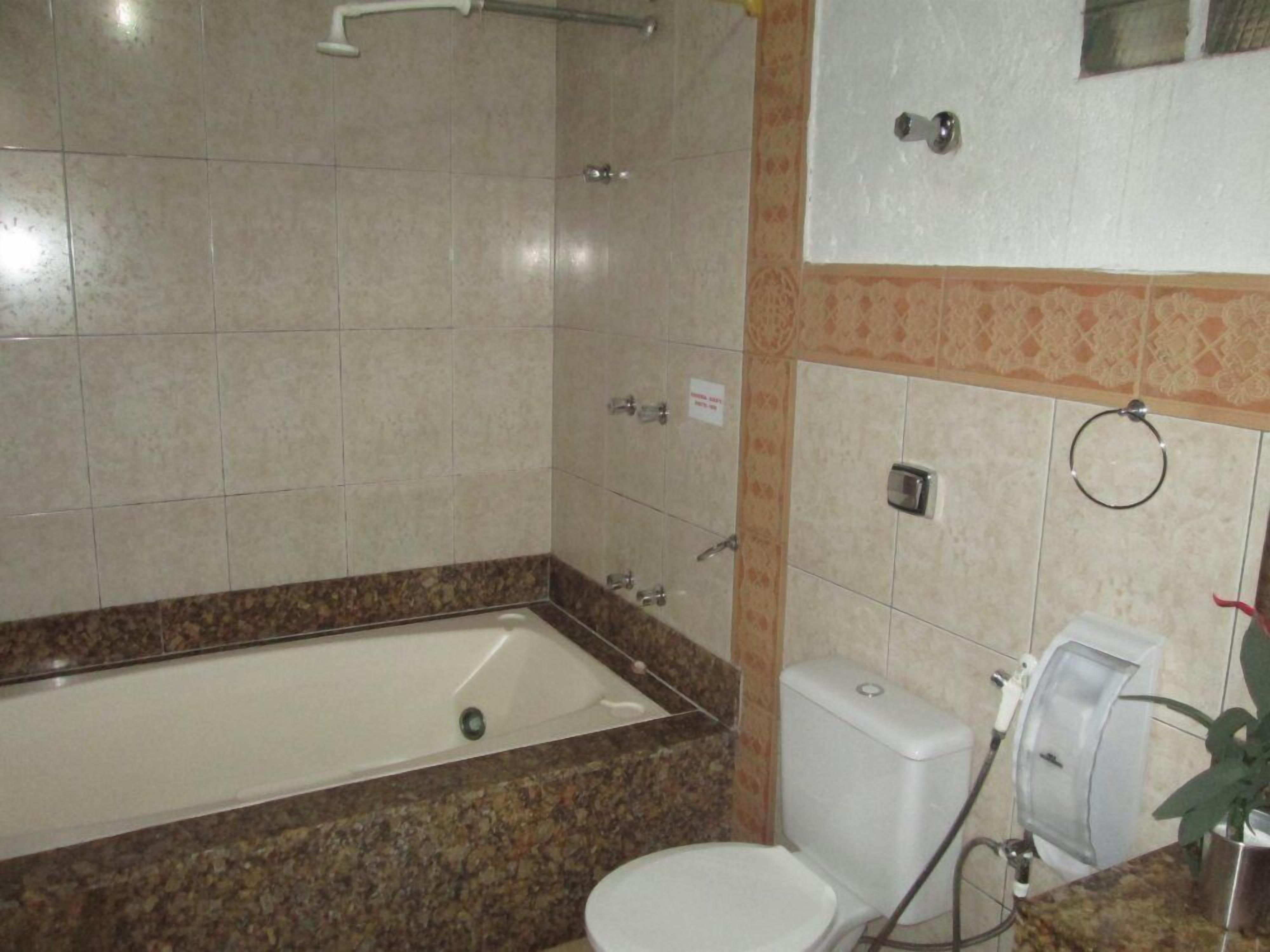 A bathroom with a bathtub, toilet, and hand dryer.