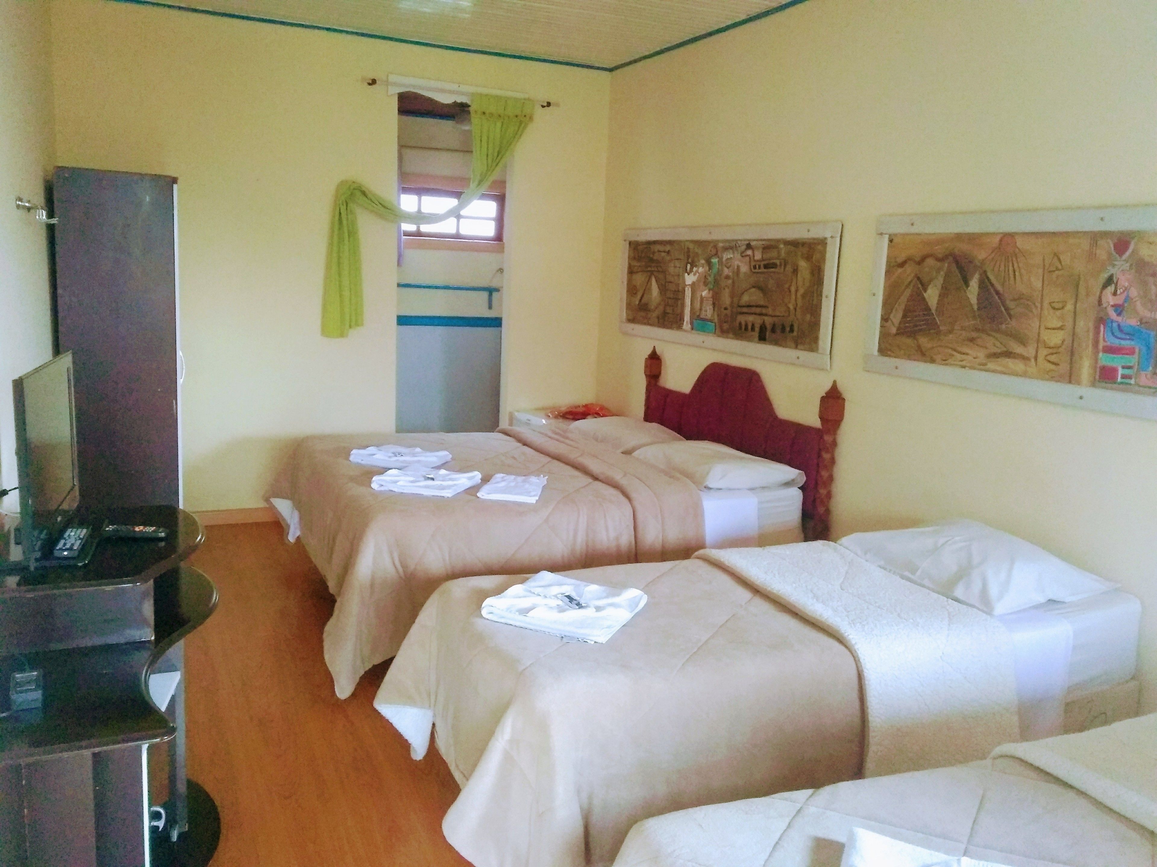 Una habitación de hotel con dos camas, un televisor y obras de arte en las paredes.