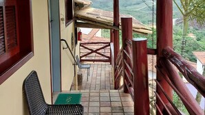 Un espacio al aire libre techado con una silla y una mesa, vistas del paisaje y una barandilla de madera.