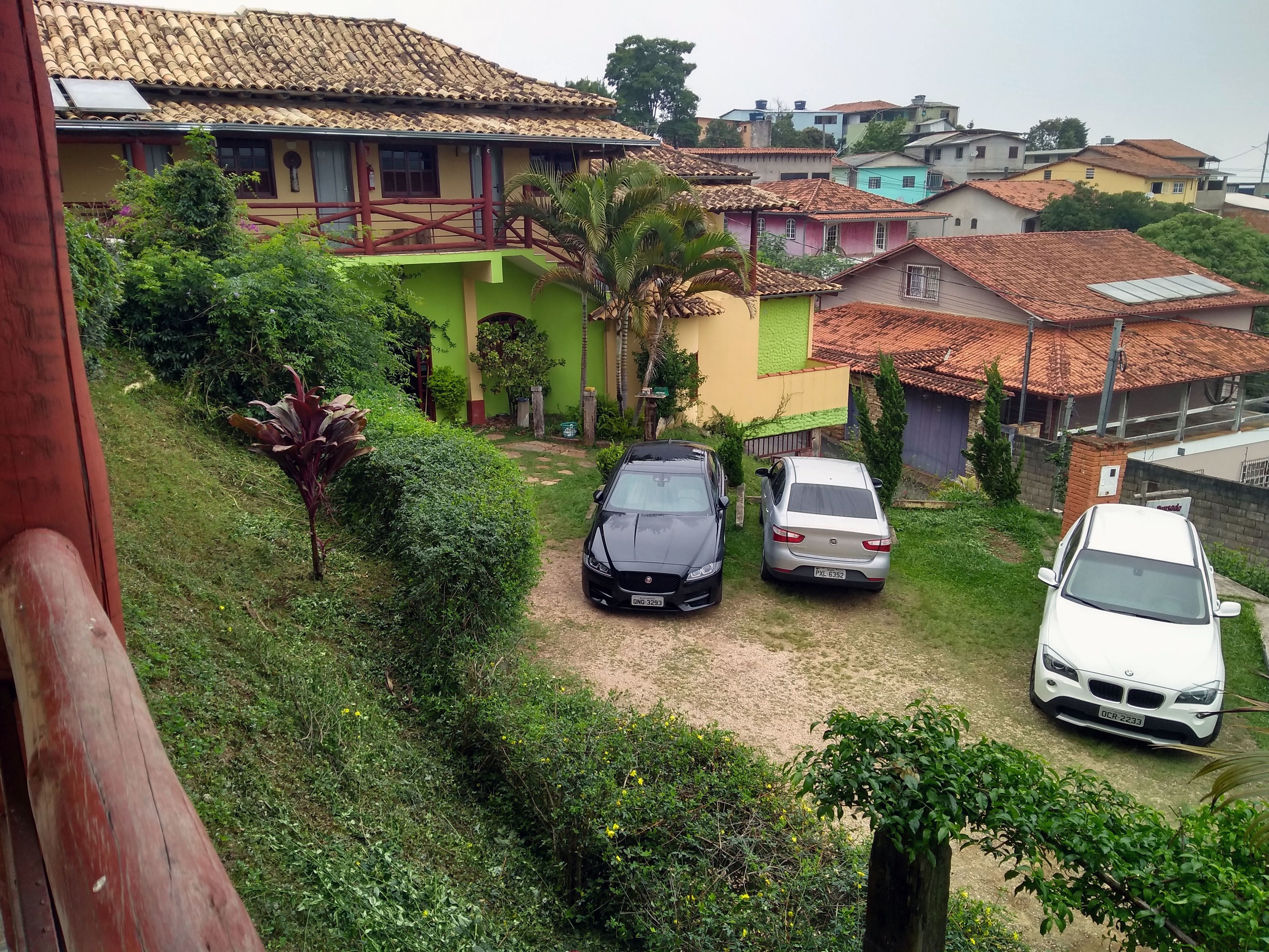 A residential area with houses, a dirt path, and parked cars.