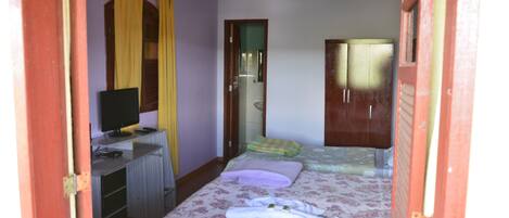 Une chambre comprenant un lit, un bureau avec un ordinateur, une armoire et un miroir.