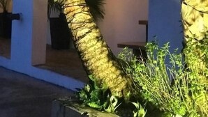 Un edificio con fachada curva, un balcón con barandilla de metal y una puerta con un cartel.