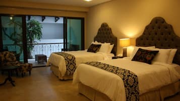 Une chambre d’hôtel avec deux lits, un balcon avec vue, une chaise et une petite table.