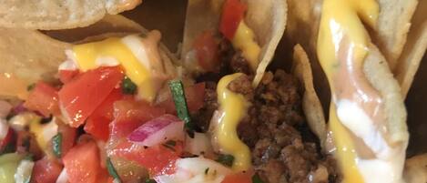 Primer plano de un plato de tacos con carne molida, tomates picados, cebollas y salsa cremosa.