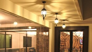 Un pasillo con un separador de vidrio que da a un comedor, una pared de piedra y una reja metálica con diseños decorativos.