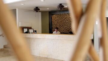 A reception desk with a modern design, a ceiling fan, and a decorative wall.