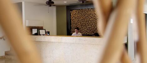 A reception desk with a modern design, a ceiling fan, and a decorative wall.