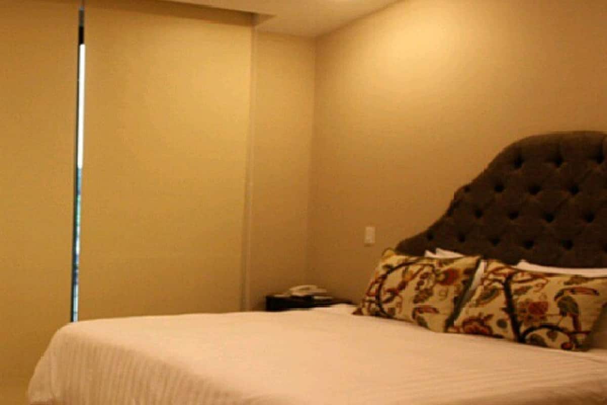 A bedroom with a bed, a nightstand, and a wall-mounted telephone.
