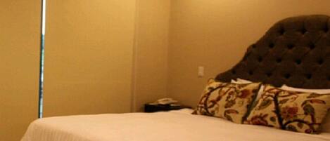 A bedroom with a bed, a nightstand, and a wall-mounted telephone.