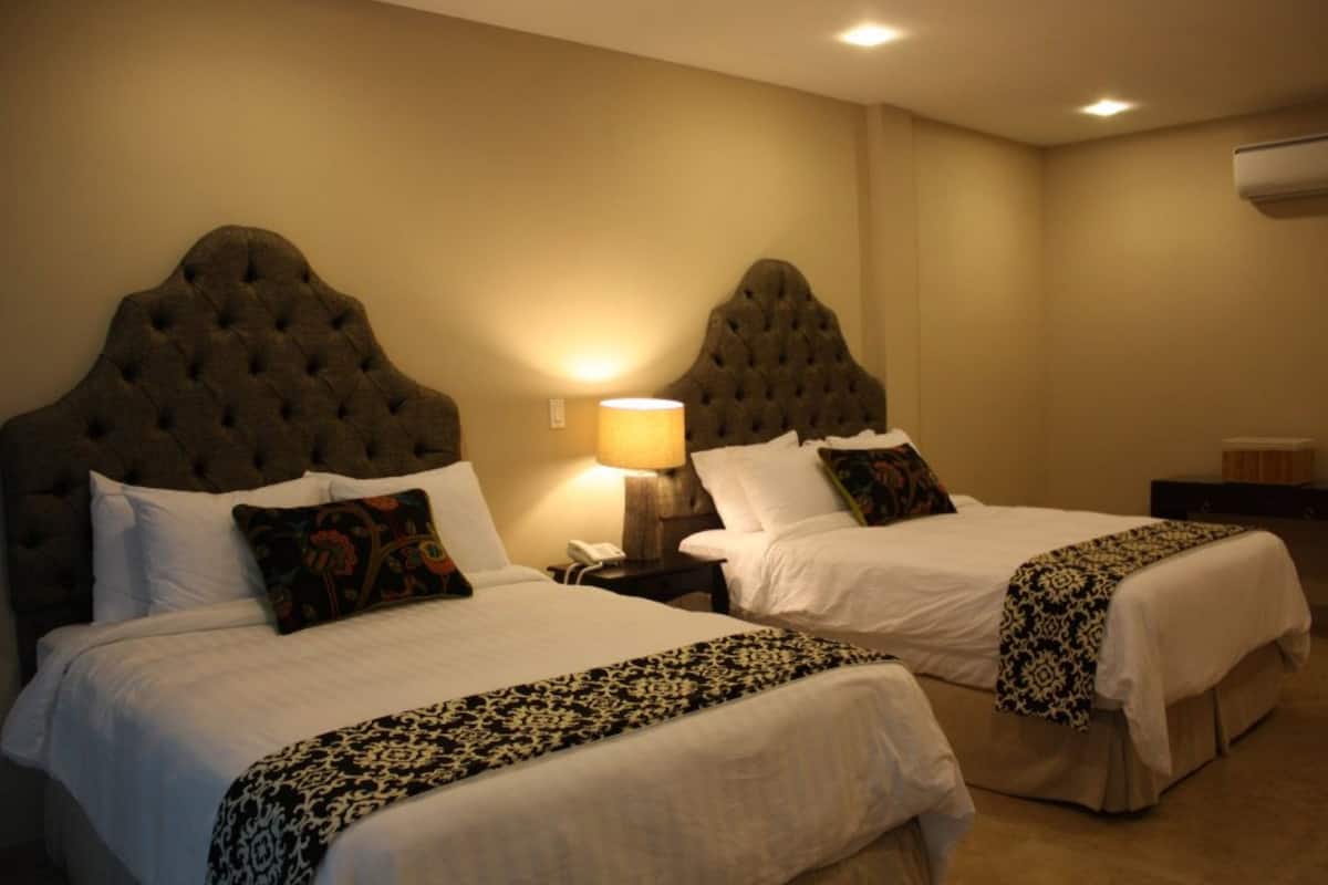 Two beds with tufted headboards, white bedding, and decorative pillows.