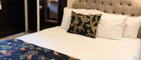 A bed with a tufted headboard, a floral-patterned bedspread, and a single decorative pillow.