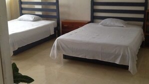 Una habitación con dos camas individuales, cada una con cabecero de madera y ropa de cama blanca.