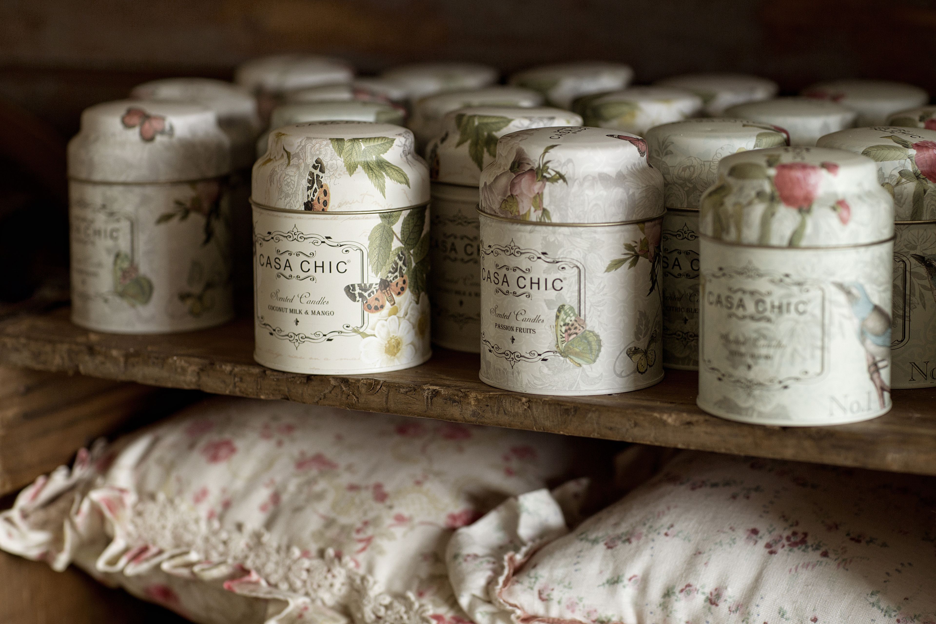 A shelf with multiple tins labeled 'Casa Chic' with floral designs.