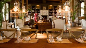 Un comedor con mesas y sillas de madera, lámparas colgantes y un ambiente acogedor.