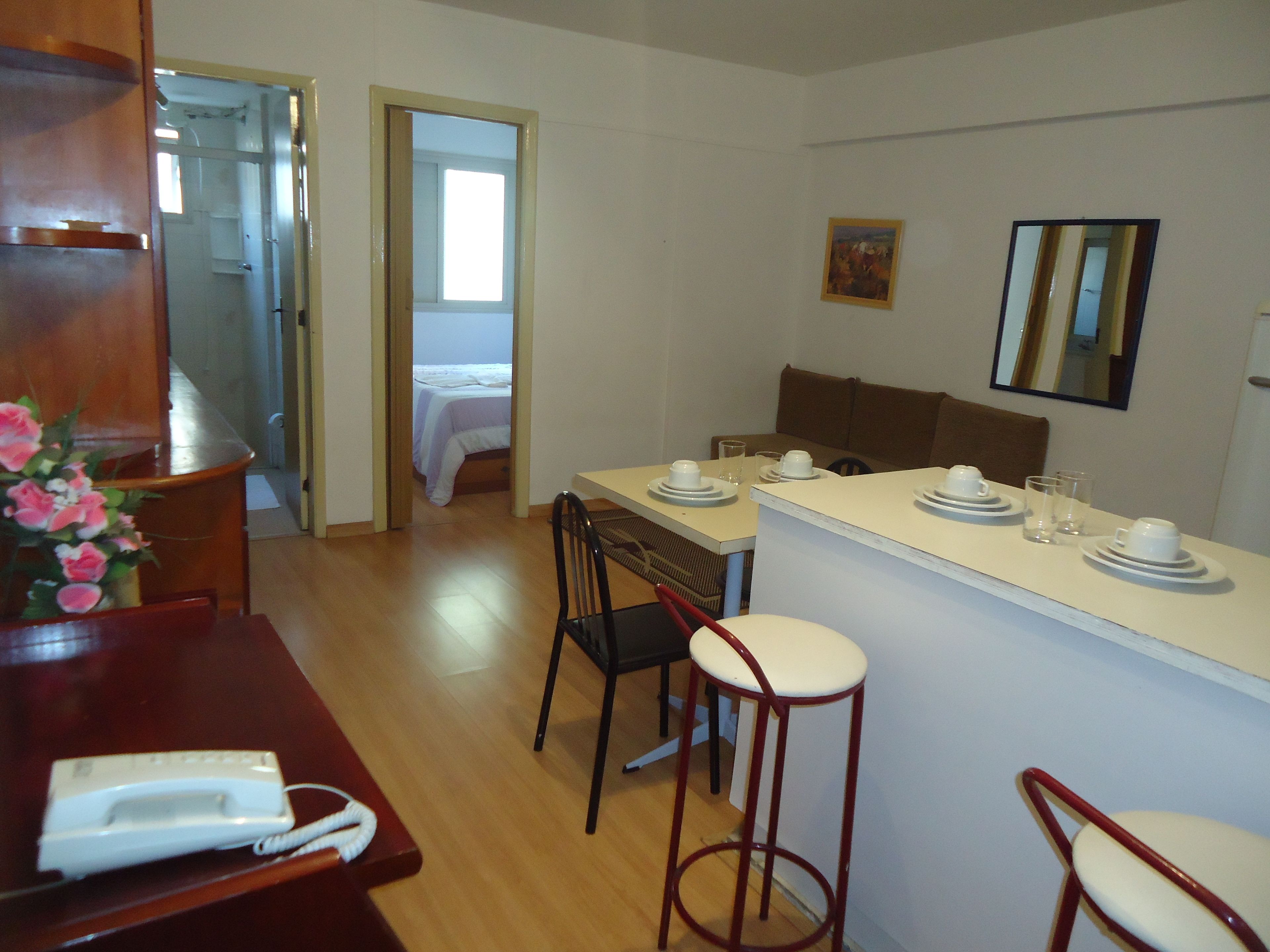 Una camera d'albergo con angolo ristoro, un letto, un bagno e uno specchio.