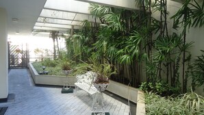 Une allée couverte avec un banc, des plantes en pot et une vue sur l’extérieur.