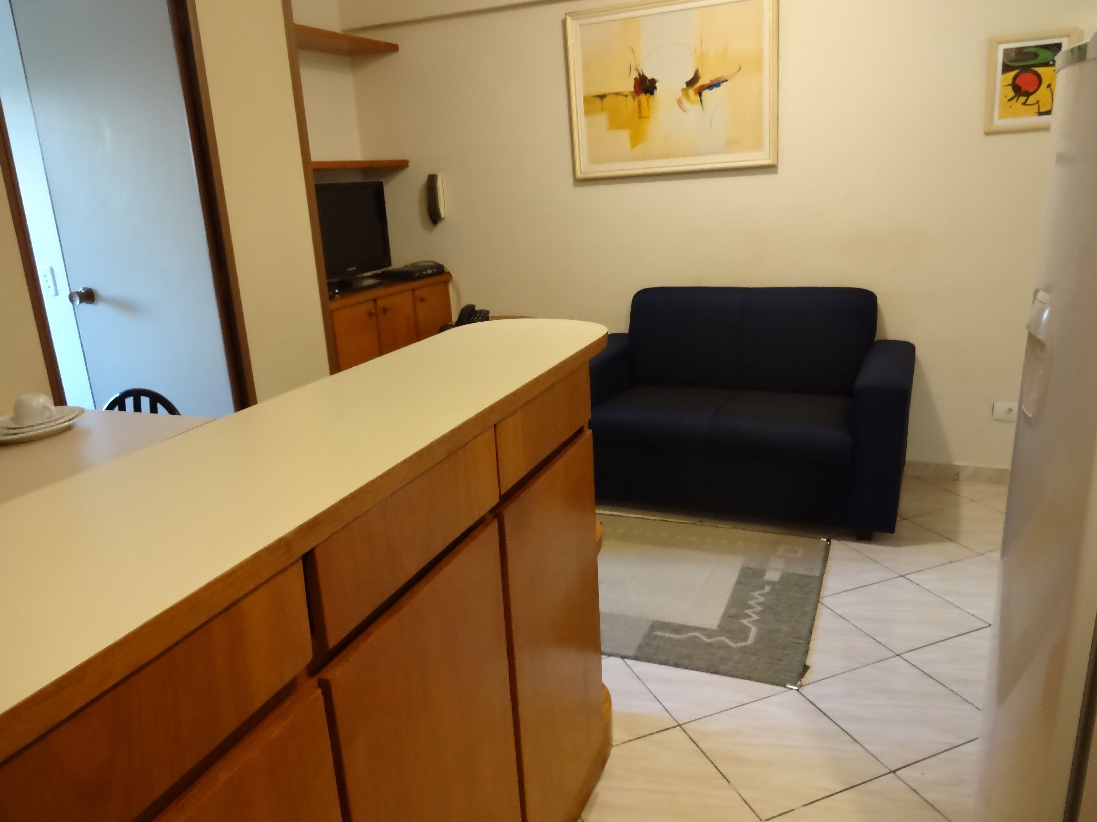 Una cucina con un bancone in legno, un divano blu scuro e un pavimento piastrellato.