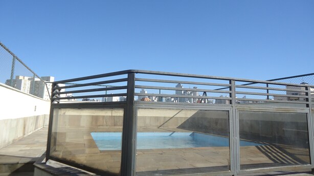 Un espace piscine sur le toit, doté d’une enceinte en verre et d’une rambarde en métal.