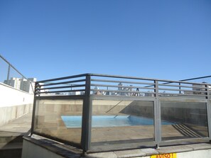 A rooftop pool area with a glass enclosure and a metal railing. - Residencial Genéve (São Paulo)