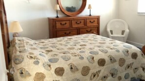 A bedroom with a bed, a dresser with drawers, a mirror, a chair, and a lamp. - Red Coconut RV Park (Fort Myers Beach)