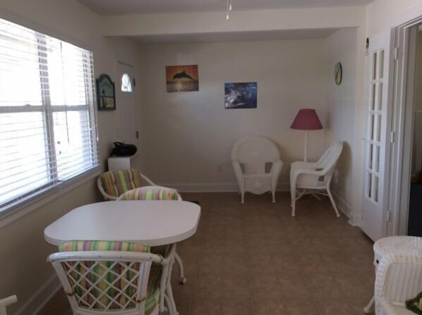 A room with a white table and chairs, a lamp, and artwork on the wall.