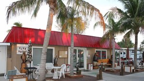 A small building with a red roof, palm trees, outdoor seating, and a sign that reads "CLUB HOUSE". - Red Coconut RV Park (Fort Myers Beach)