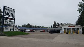 A motel with a liquor store, multiple parked vehicles, and a building with a signboard.