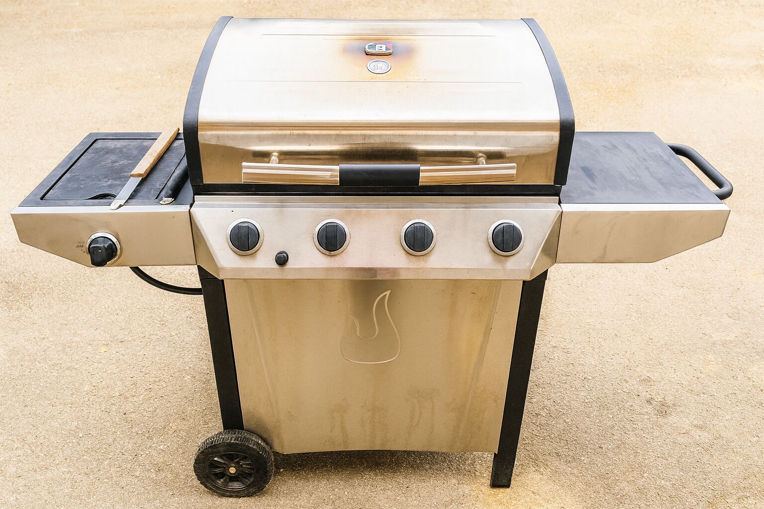 Een draagbare gasgrill met vier bedieningsknoppen, een digitaal display en een extra brander.