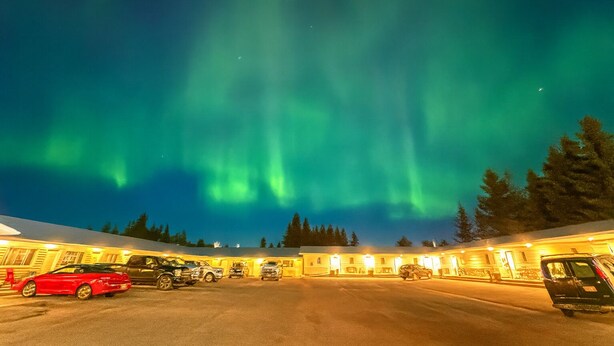 A hotel with a parking lot and a view of the Northern Lights.