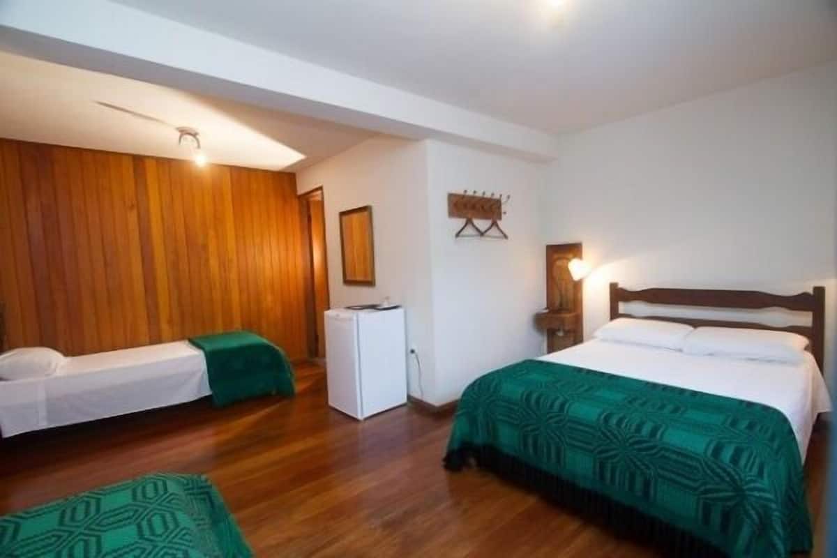 A hotel room with two beds, a refrigerator, and a wooden wall.