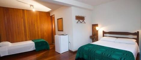 A hotel room with two beds, a refrigerator, and a wooden wall.