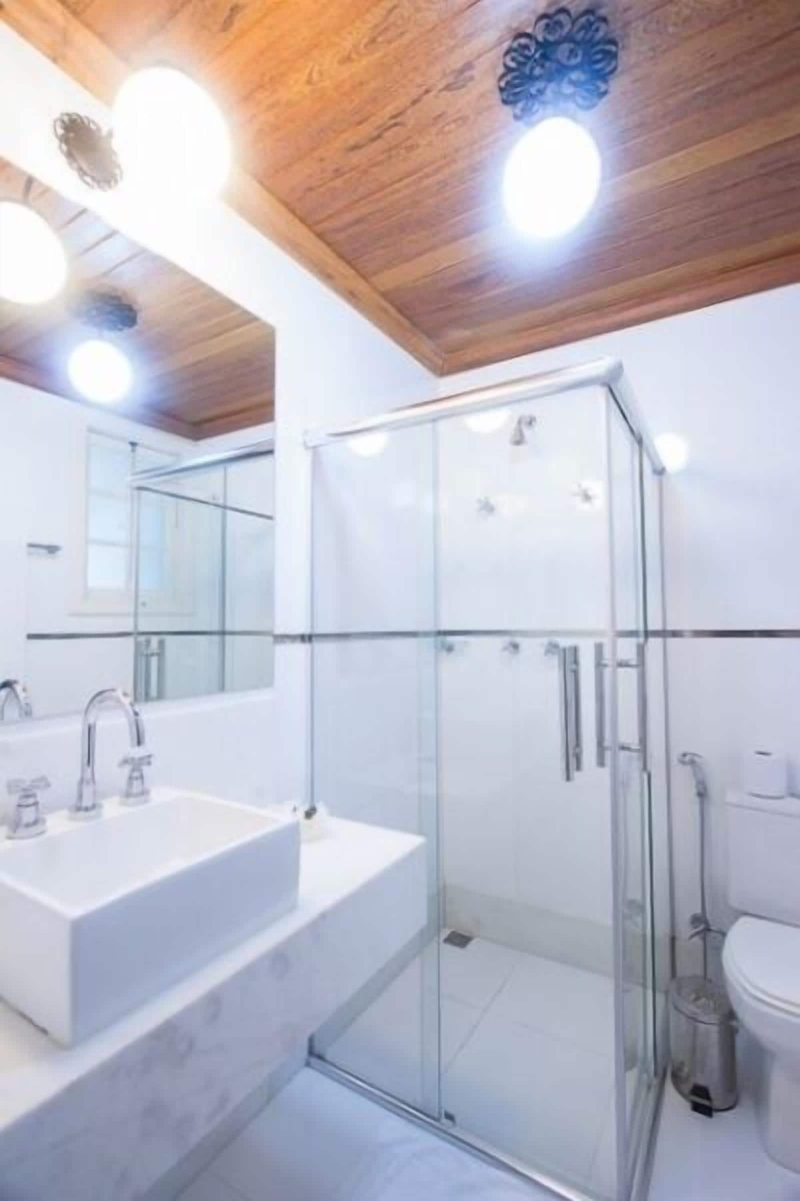 A modern bathroom with a glass shower enclosure, a large mirror, and a white sink.
