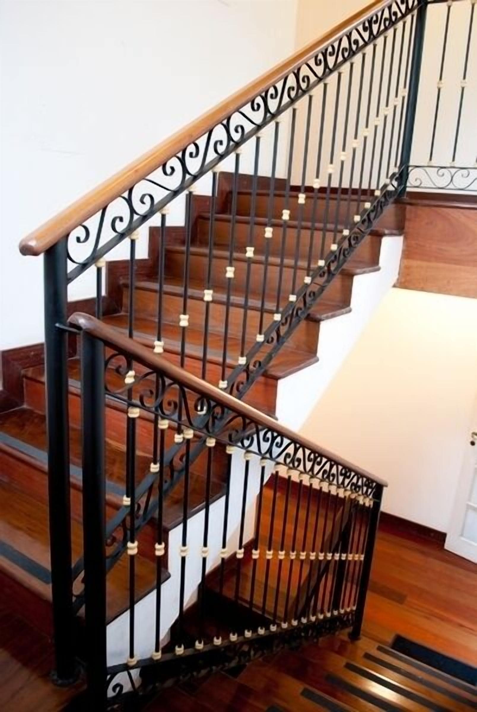 A wooden staircase with black metal railings and a handrail.
