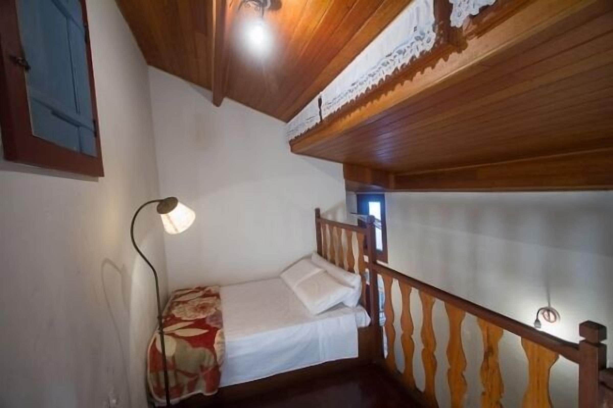 A small, cozy room with a single bed, a wooden ceiling, and a simple nightstand.