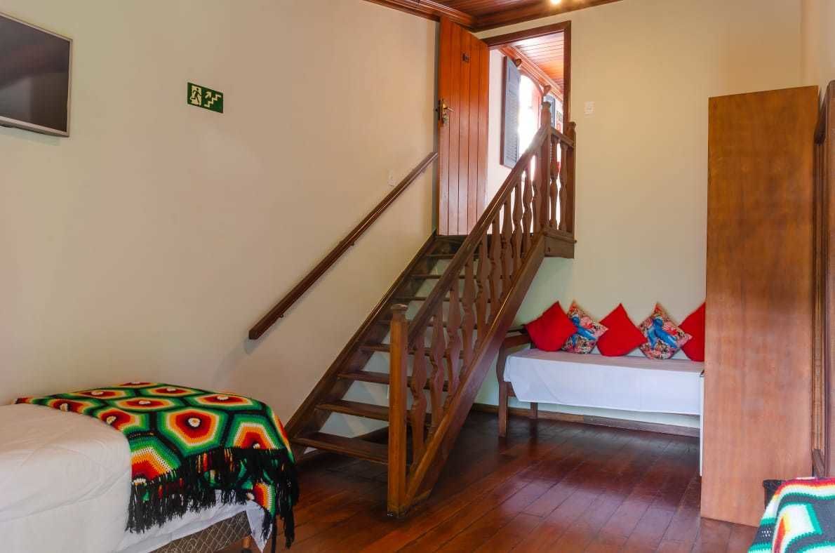 Una escalera con barandillas de madera que lleva a una habitación con una cama y un banco.