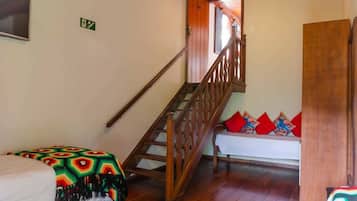 Una escalera con barandillas de madera que lleva a una habitación con una cama y un banco.