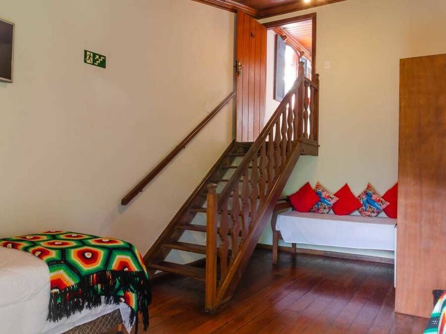Una escalera con barandillas de madera que lleva a una habitación con una cama y un banco.