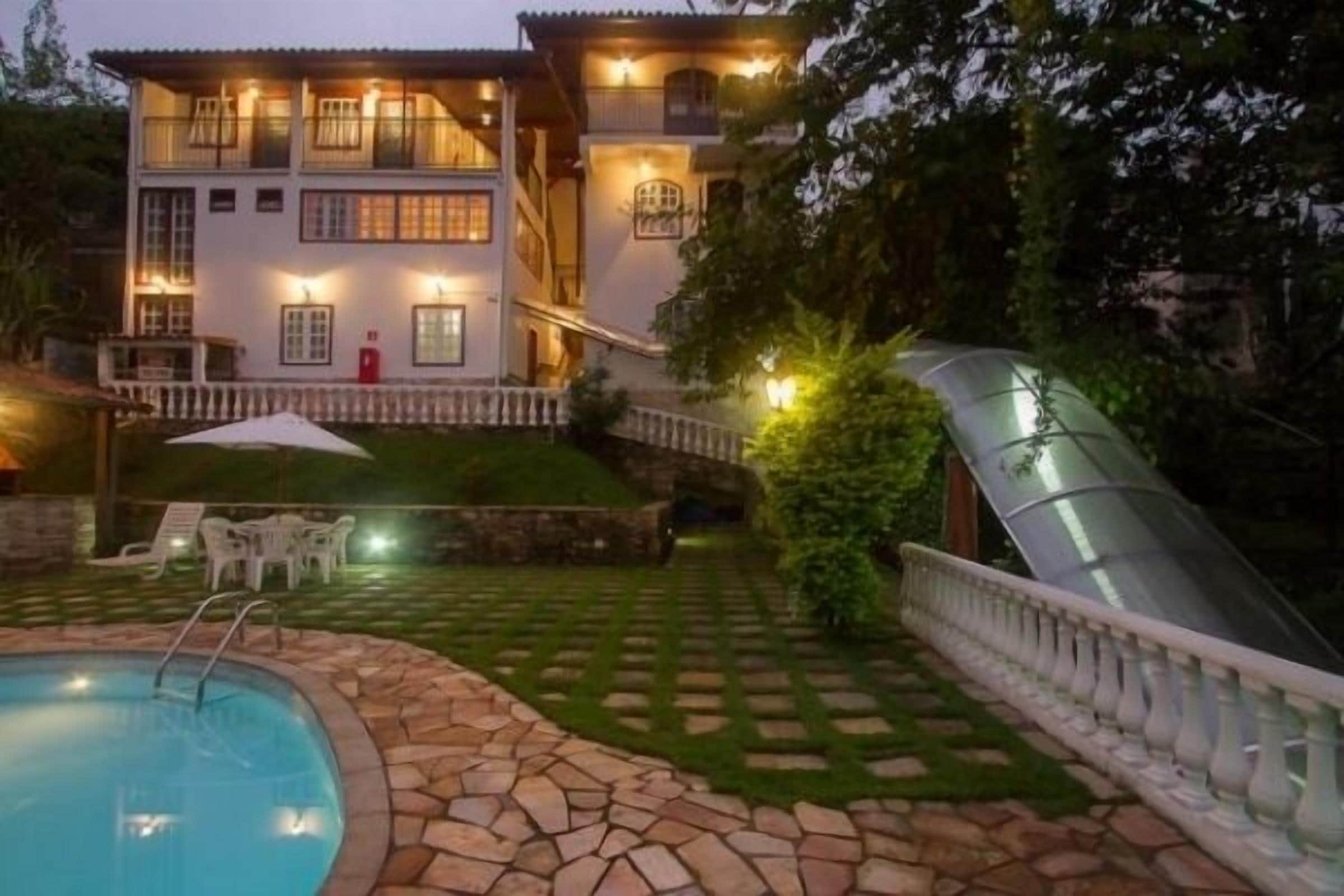 A two-story house with a swimming pool, stone pathway, and a glass slide.