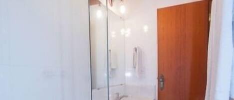 A modern bathroom with a glass shower enclosure, a wooden ceiling, and a white sink.