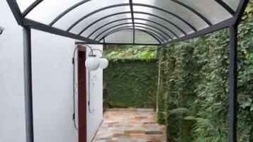 Un corridoio coperto con pavimento in pietra e verdeggiante vegetazione sulle pareti.