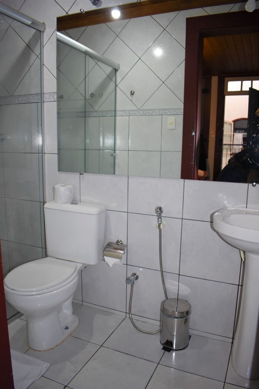 A bathroom with a toilet, bidet, sink, and a trash can.