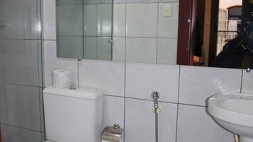 A bathroom with a toilet, bidet, sink, and a trash can.