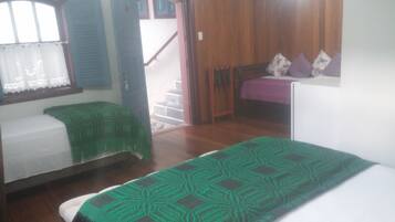 A room with two beds, a wooden door, and a window with curtains.