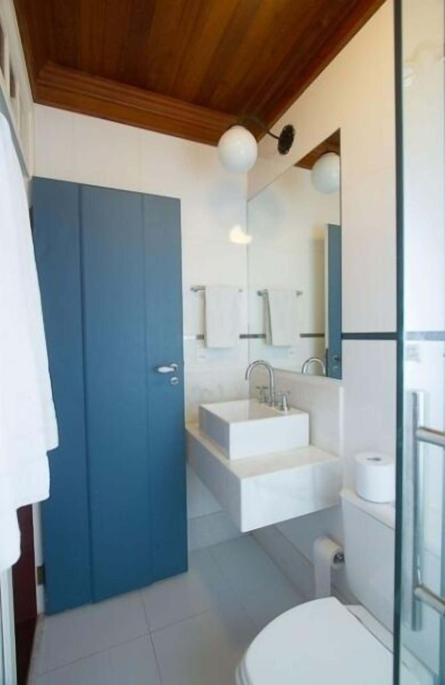A modern bathroom with a blue door, white sink, and toilet.