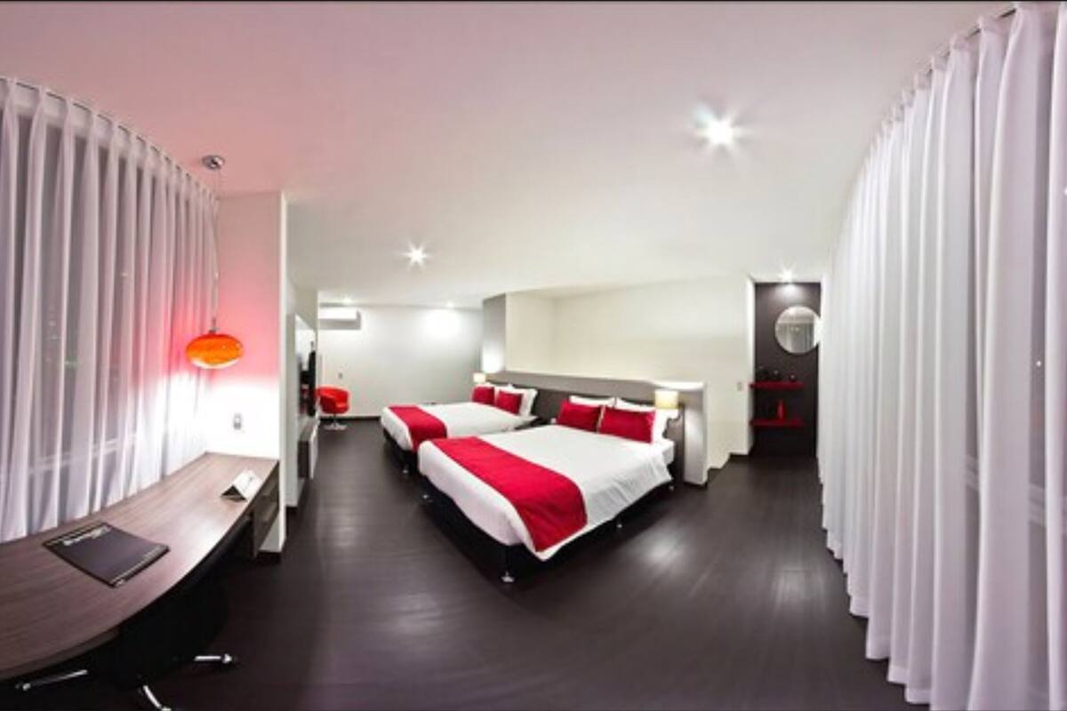 Ein modernes Hotelzimmer mit zwei Betten, einem Schreibtisch und einem Spiegel.