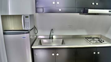 Una cocina moderna con electrodomésticos de acero inoxidable, incluyendo un microondas, fregadero y estufa a gas.