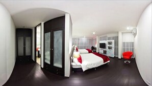 Quarto de hotel moderno com uma cama grande, uma cadeira vermelha e uma televisão.