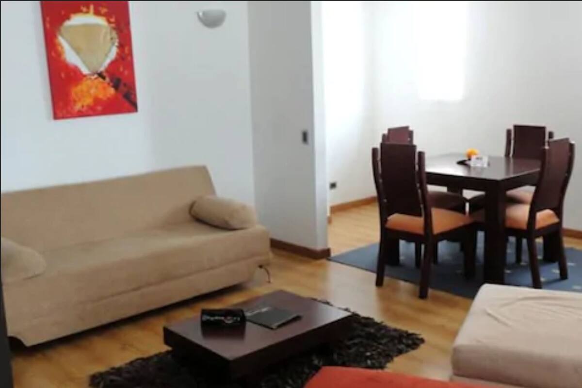 Ein Wohnzimmer mit einer Couch, einem Couchtisch und einem Esstisch mit Stühlen.