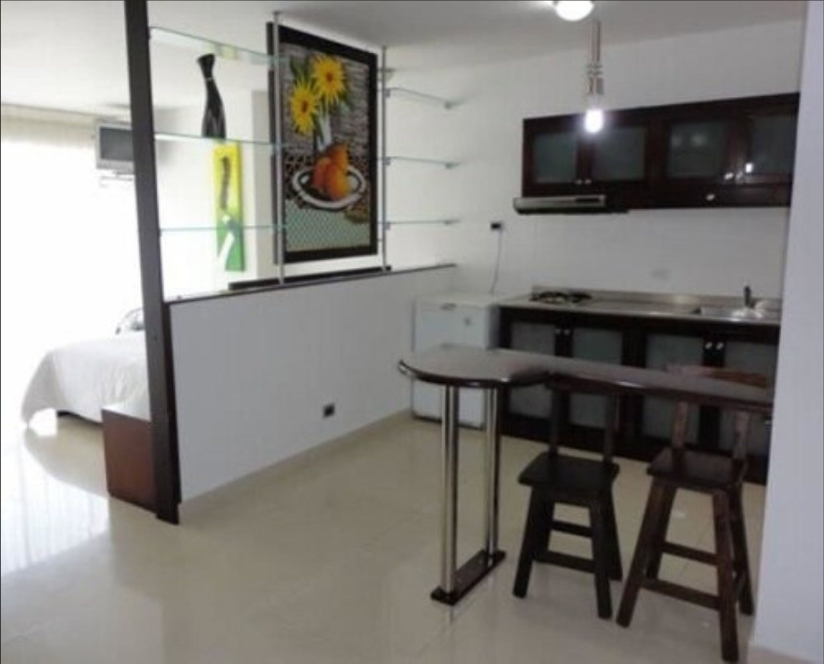A compact kitchen with a dining area, a bed, and a TV.